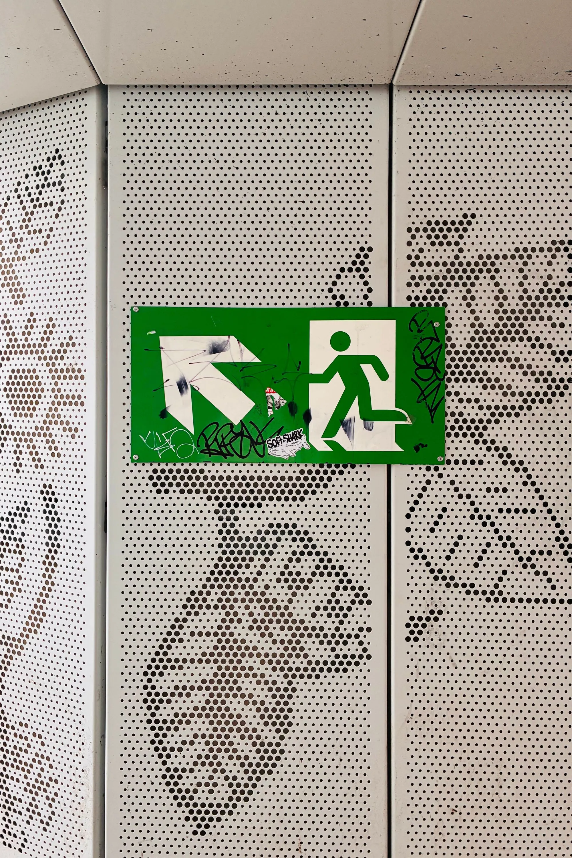 Exit sign pointing to the top-left covered in grafitti