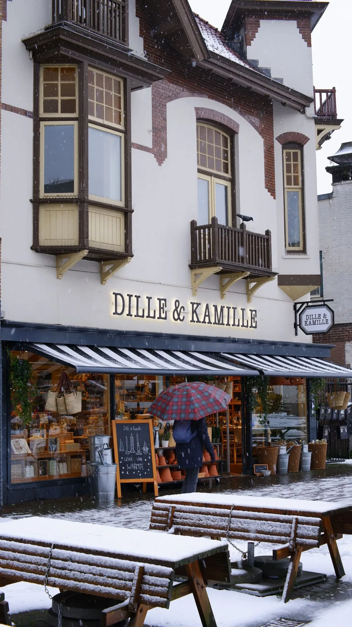 Snow in front of storefront with person walking by