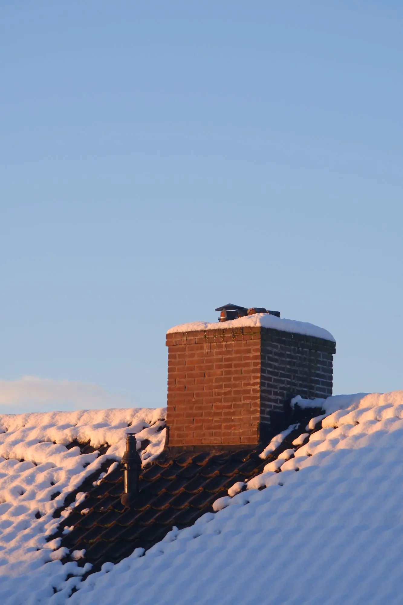 Snow on roof with sun hitting the chimney