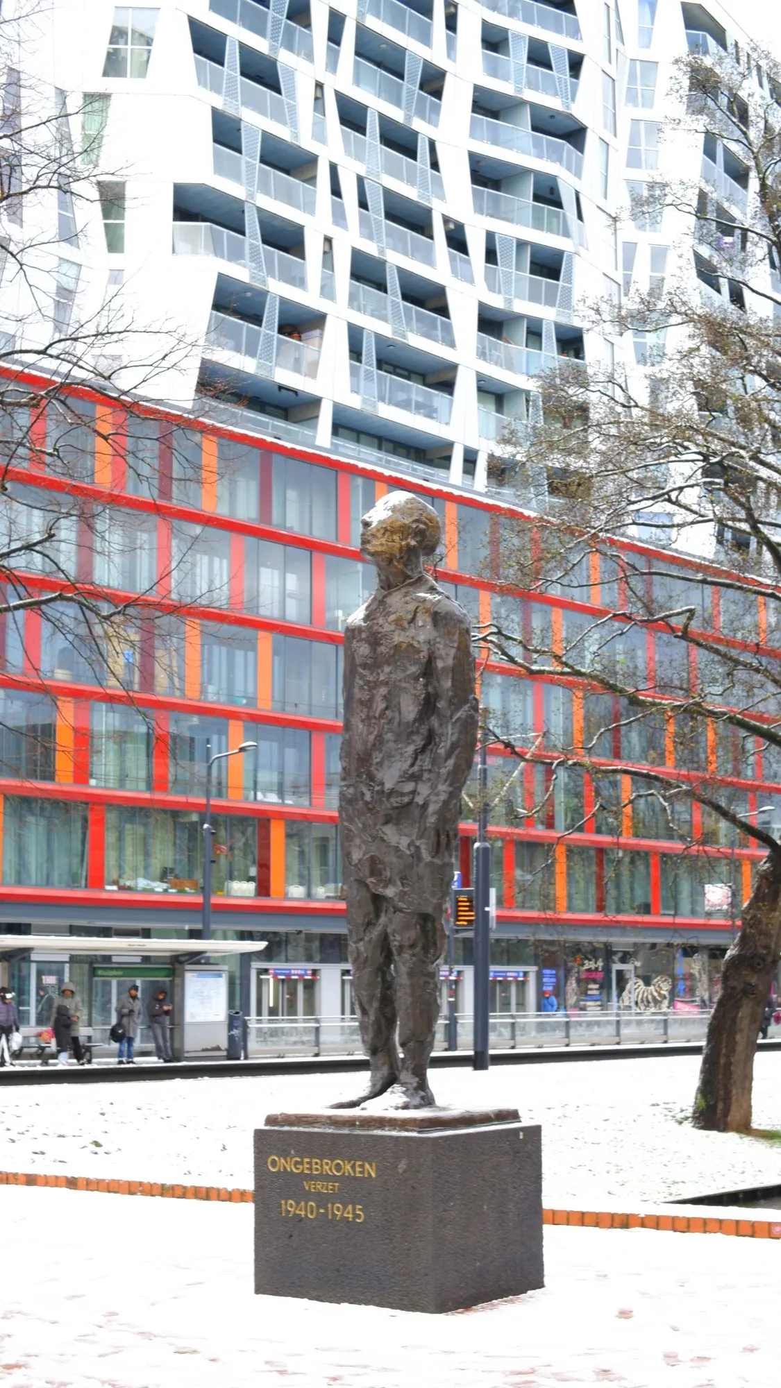 Statue of man in front of white and red buildings