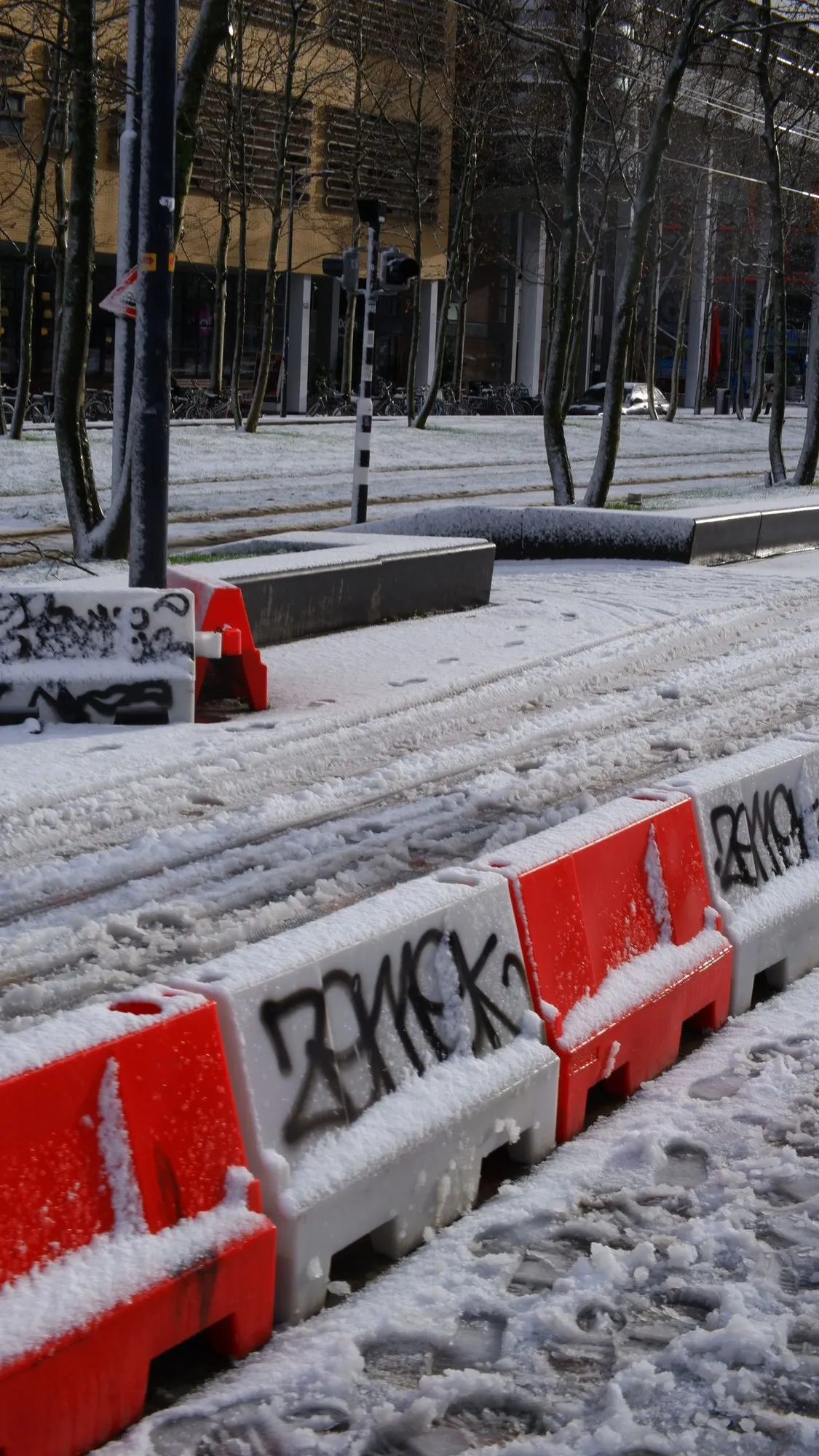 Street covered in the snow with red and white barriers