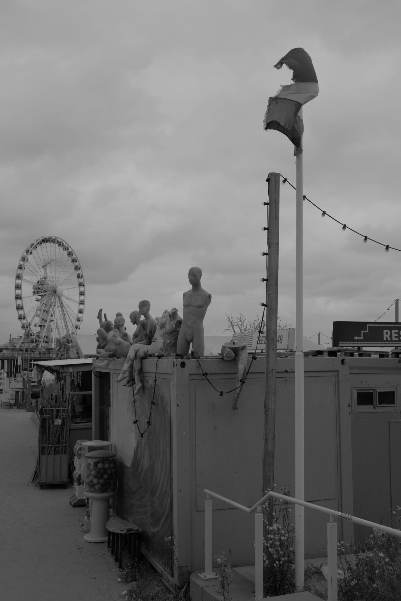 2026-07-18 - xt15-45 - bw - NL - Scheveningen - Creepy manequins on top of building with ferris wheel in background