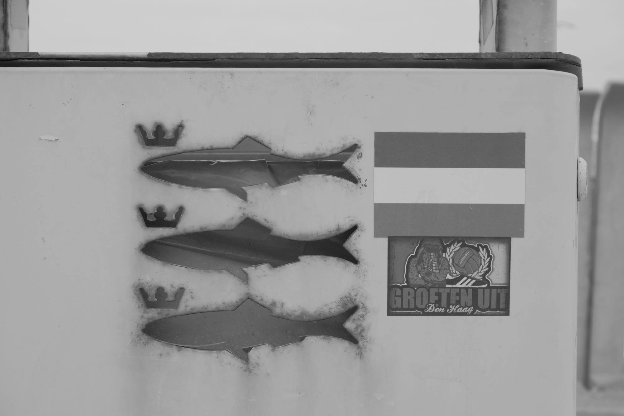 2026-07-18 - xt15-45 - bw - NL - Scheveningen - Three fish with crowns next to a dutch flag on the side of a bin