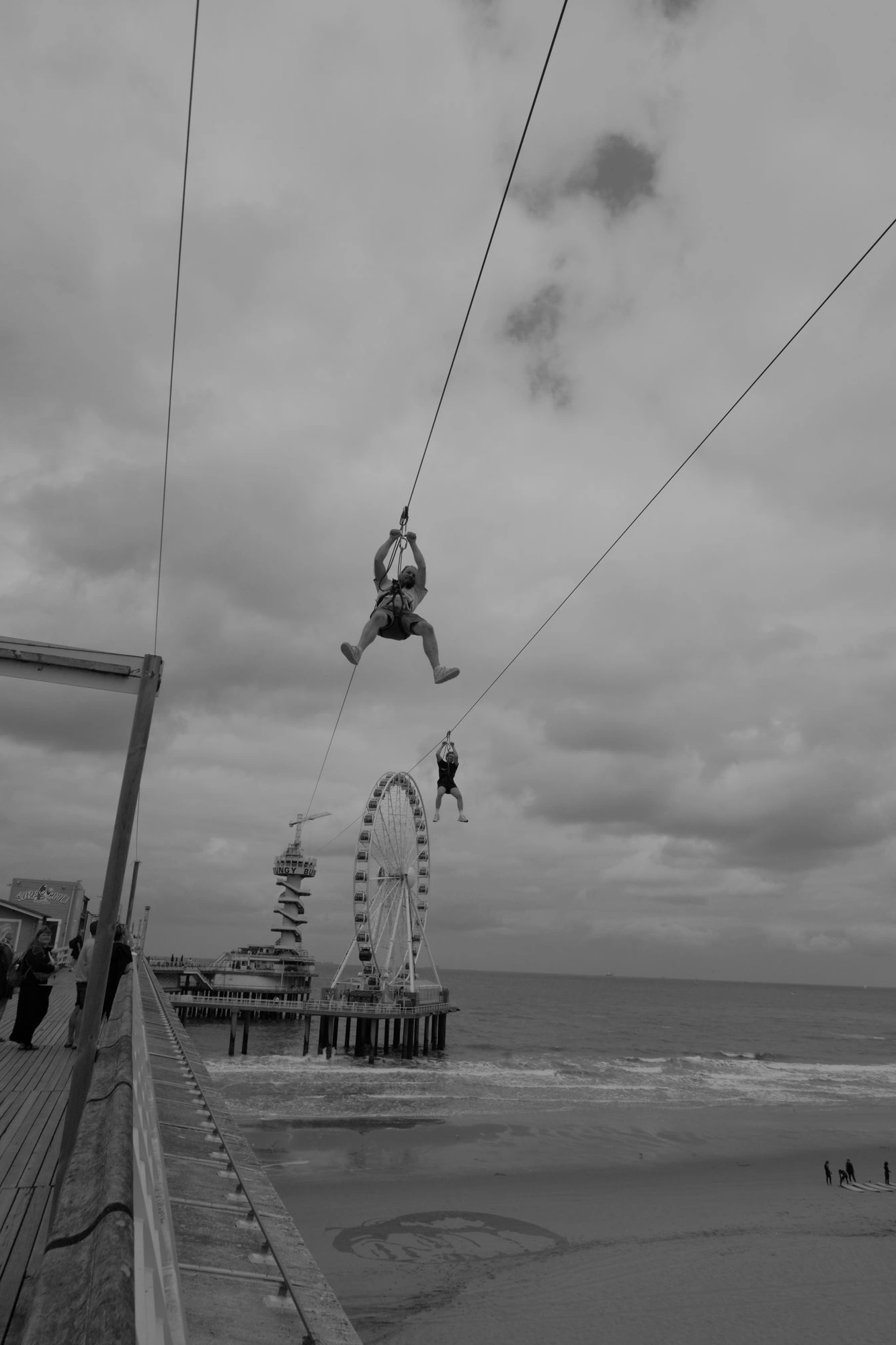 2026-07-18 - xt15-45 - bw - NL - Scheveningen - People on zipline with ferris wheel and see in background