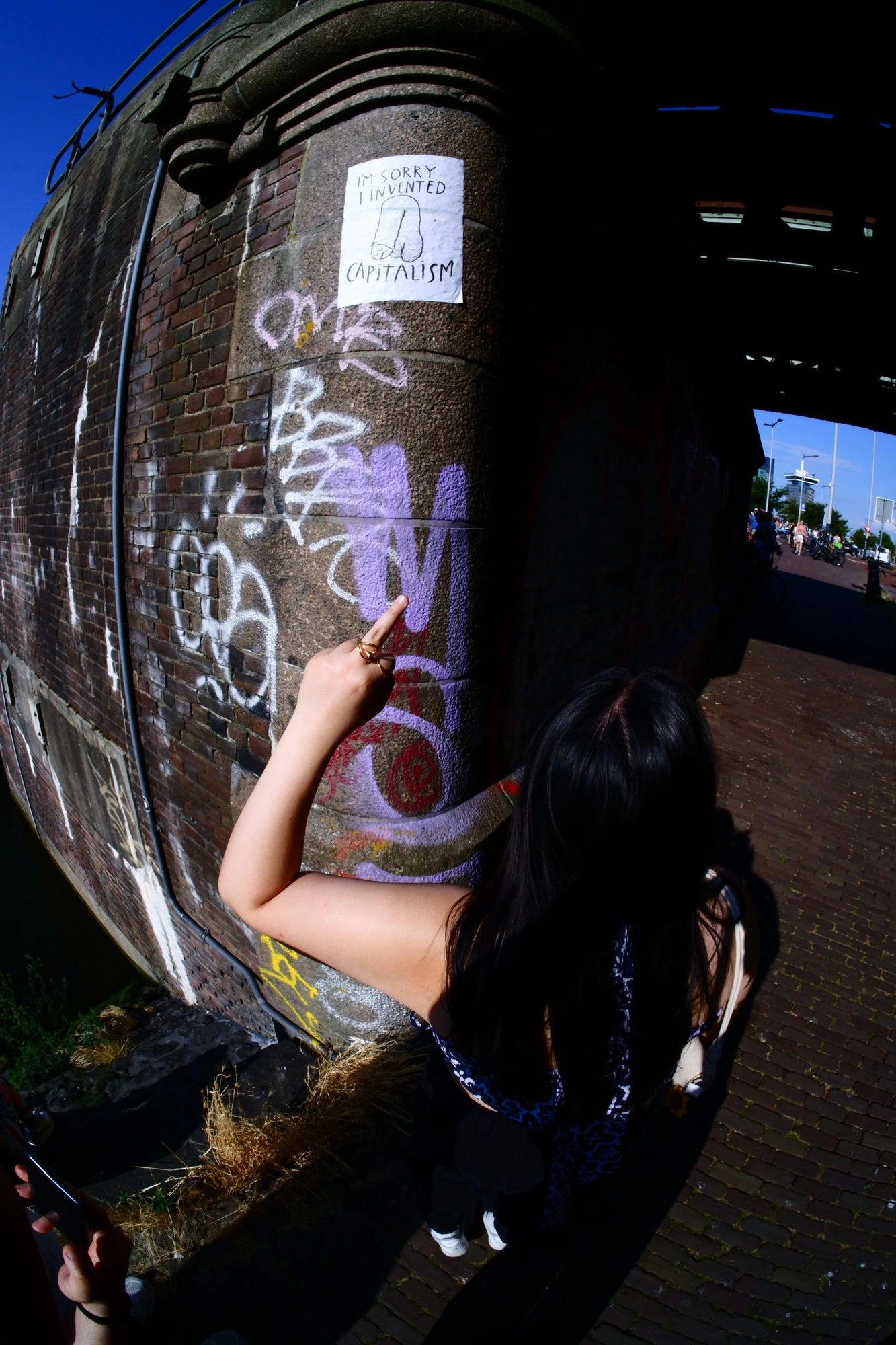 2026-08-01 - xt7.5 - color - NL - Amsterdam - Person pointing at sign saying "I'm sorry I invented capitalism"