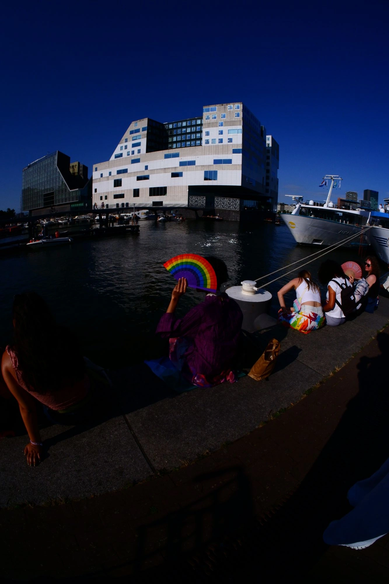 2026-08-01 - xt7.5 - color - NL - Amsterdam - Person with rainbow fan sitting on side of the IJ