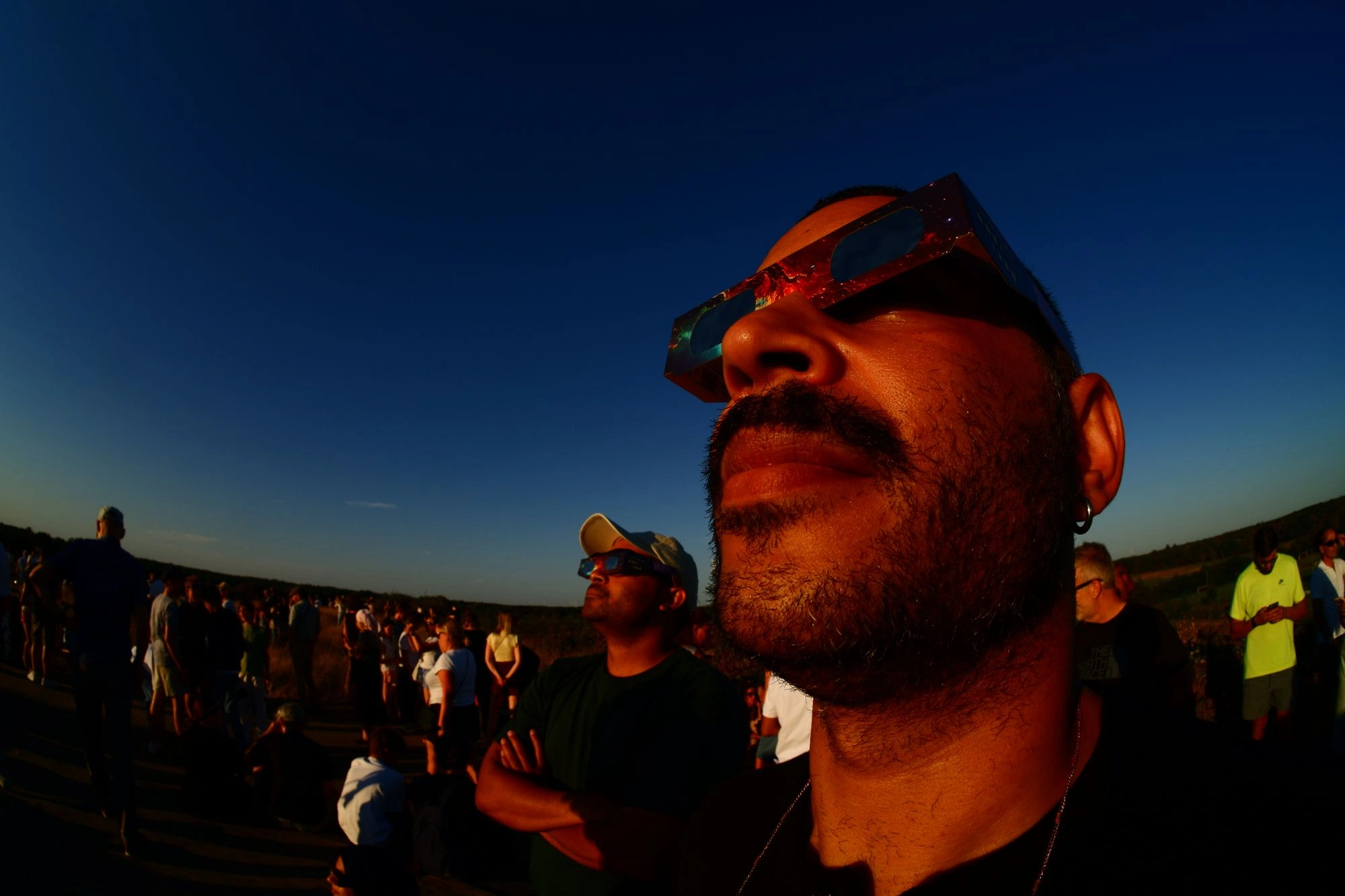 Closeup of person wearing eclipse glasses staring at the sun
