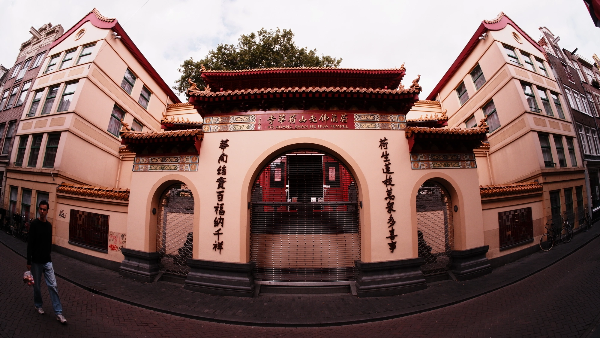 Peach Chinese-style building with person walking at the edge of the frame
