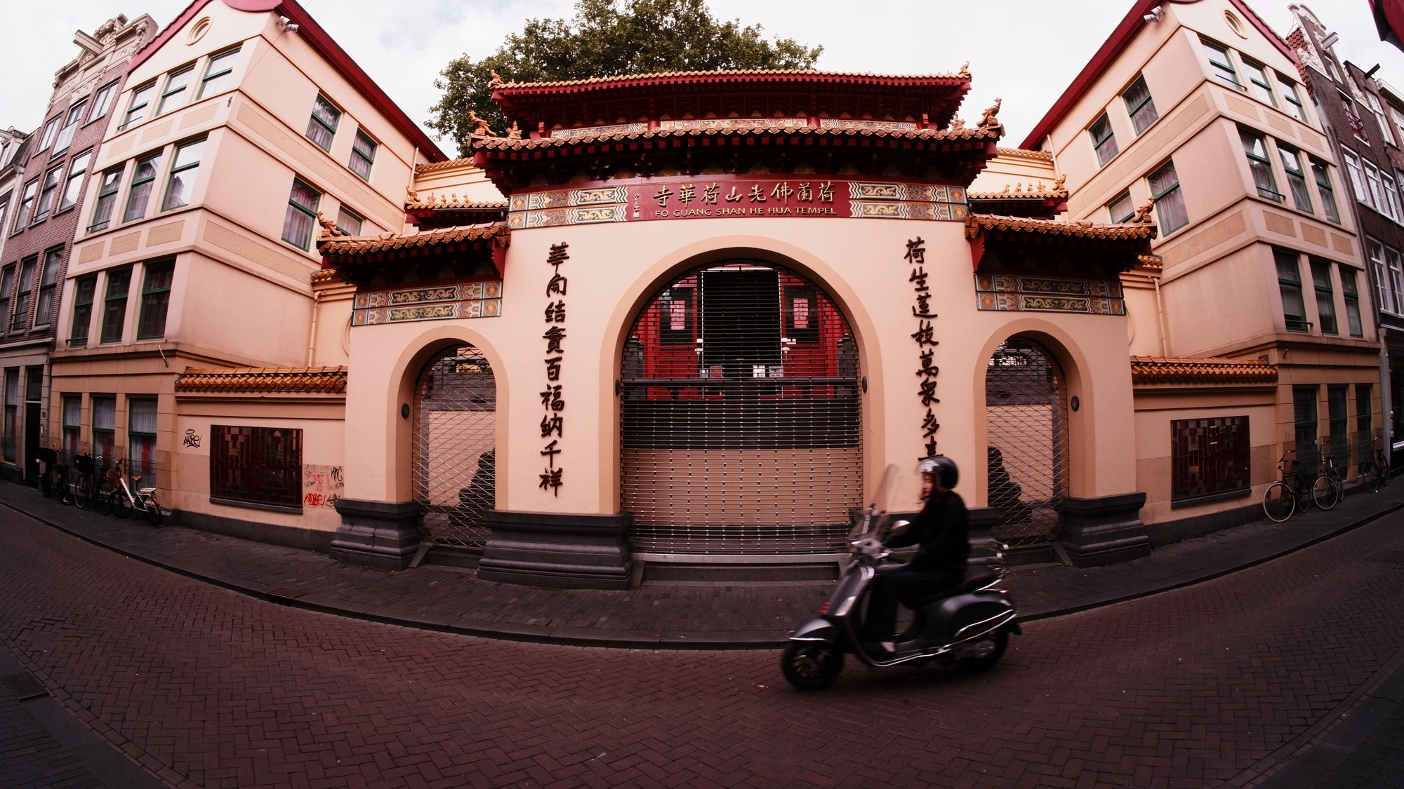 Peach Chinese-style building with scooter zooming past