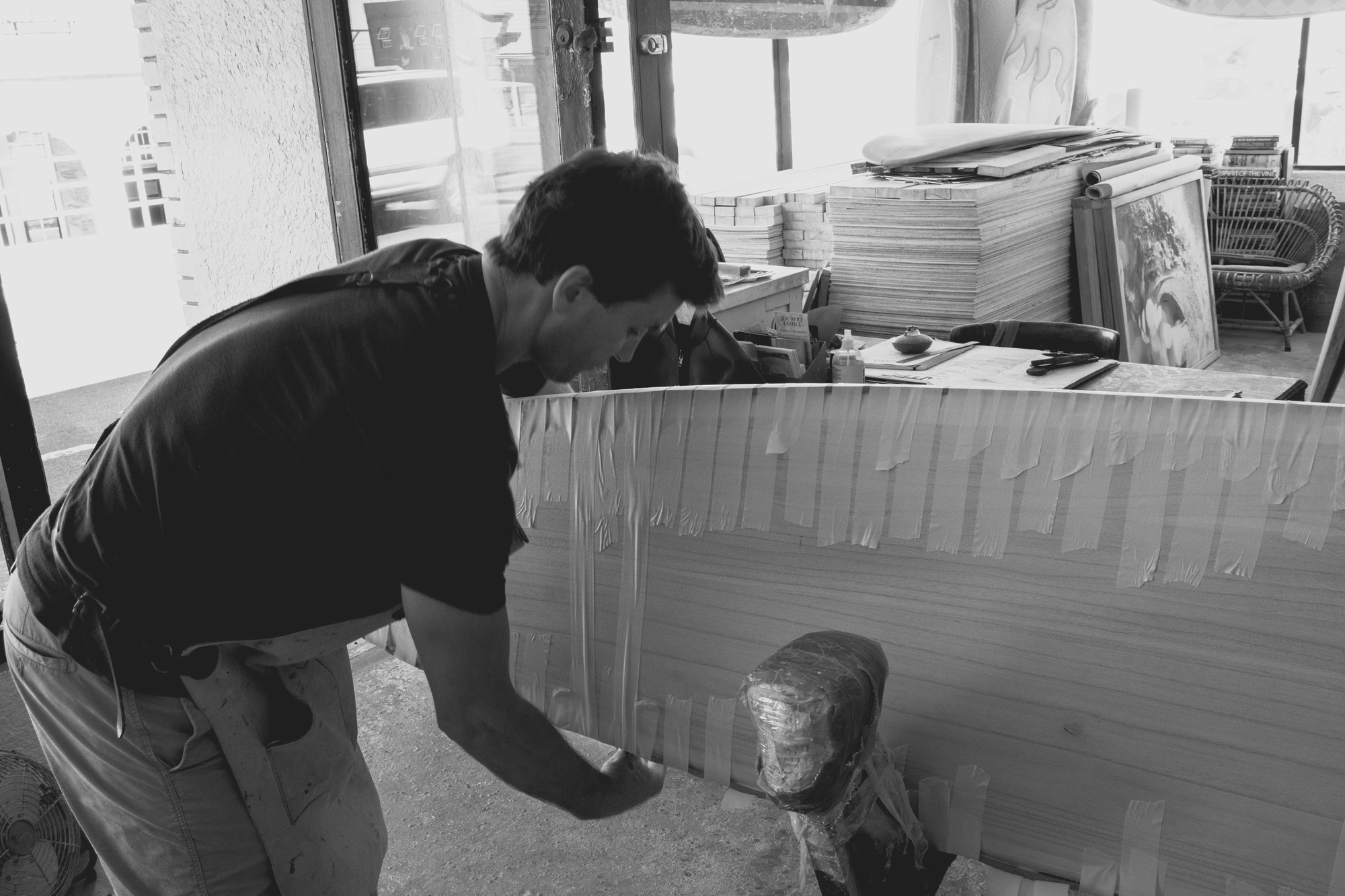 2022-02-14 - xt15-45 - bw - ZA - Cape Town - Man wraps surfboard in masking tape during construction
