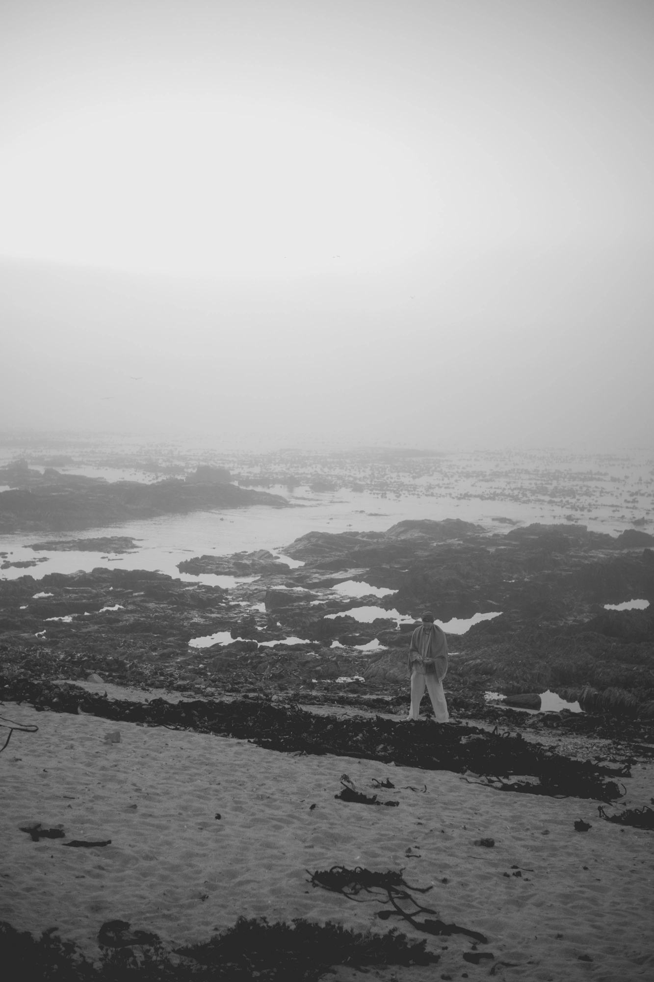 2022-02-15 - xt35 - bw - ZA - Cape Town - Ocean with man picking up shells on a misty day