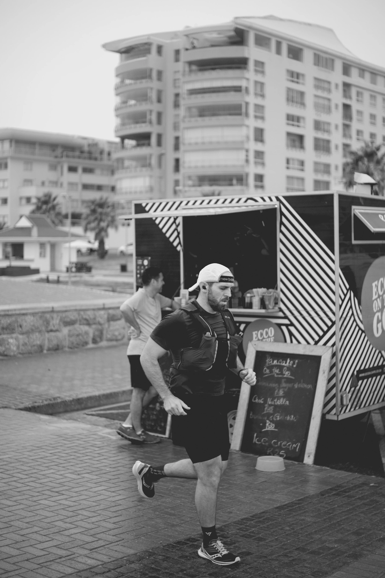 2022-02-18 - xt35 - bw - ZA - Cape Town - Man running in front of coffee cart
