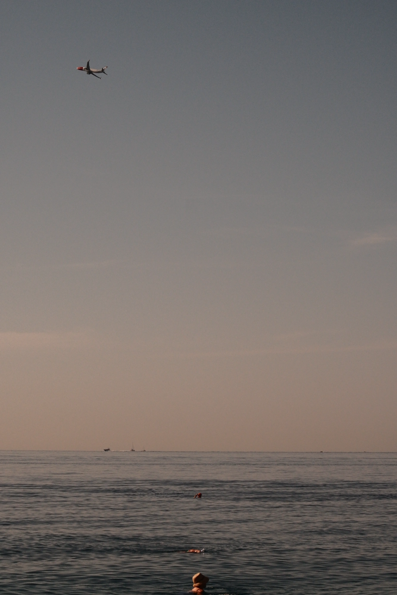 Person in water with plane flying in the distance