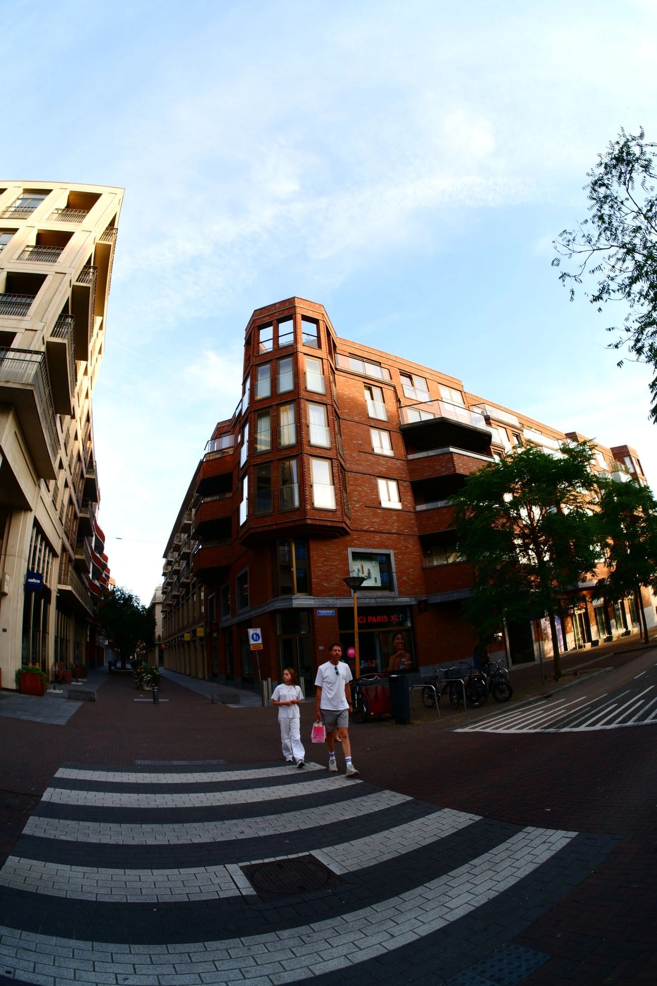 Two people crossing road in front of red brick building