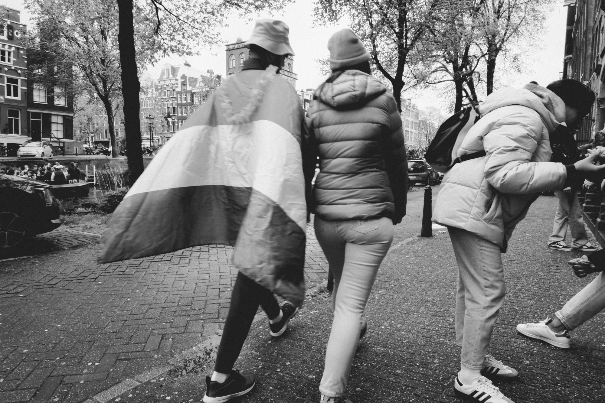 2024-04-26 - xt15-45 - bw - NL - Amsterdam - Person walking with flag on their back