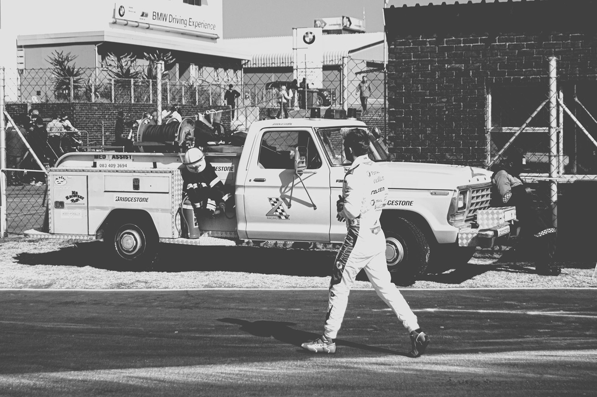 2019-07-27 - n18-55 - bw - ZA - Zwartkops Raceway - Driver walks across track with tow truck in the background