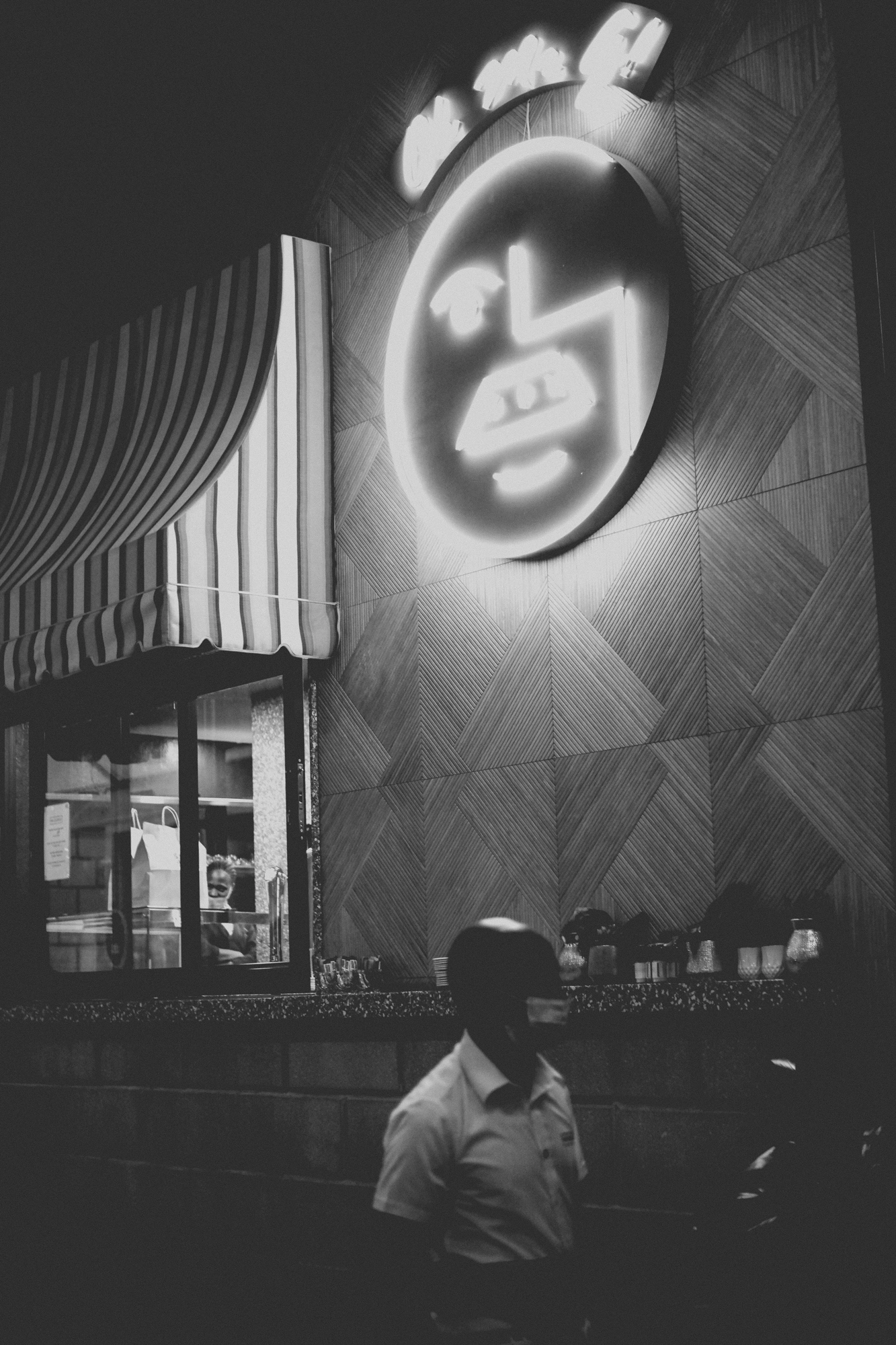 2021-12-04 - xt15-45 - bw - ZA - Melrose Arch, Johannesburg -  Waiter walking in front of restuarant sign