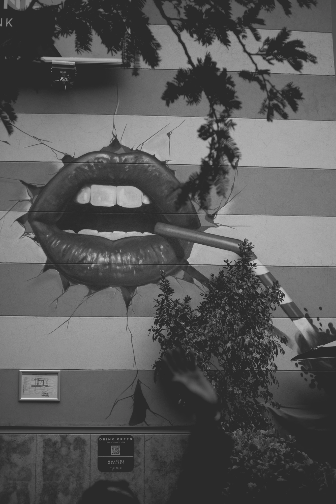 2021-12-19 - xt35 - bw - ZA - Rosebank, Johannesburg - Cigarette and lips painted on the wall, waving security guard