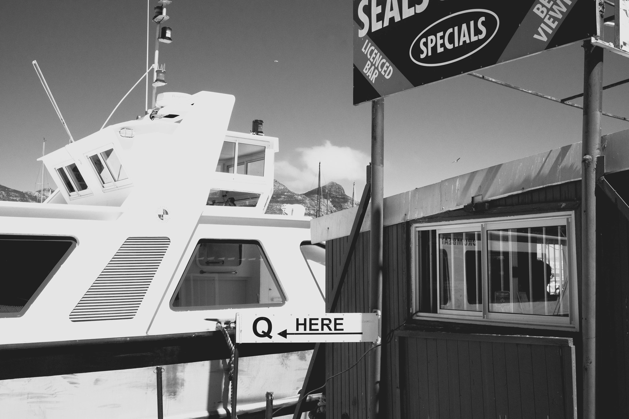 2022-02-13 - Cape Town - A ticket booth beside a boat with a sign reading 'Q Here'.j