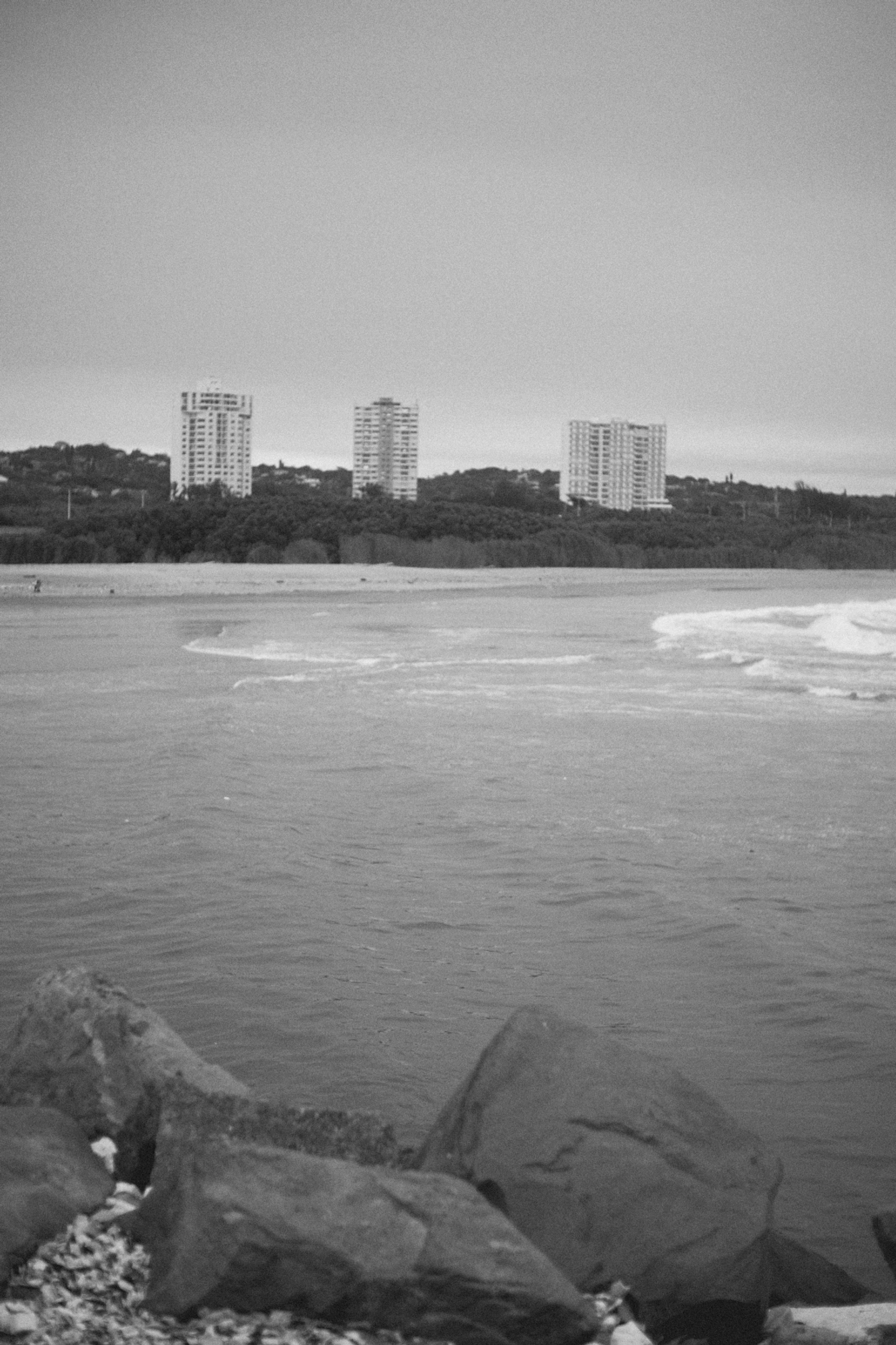 2022-09-21 - Durban -  Rocks with buildings in background over the ocean.j