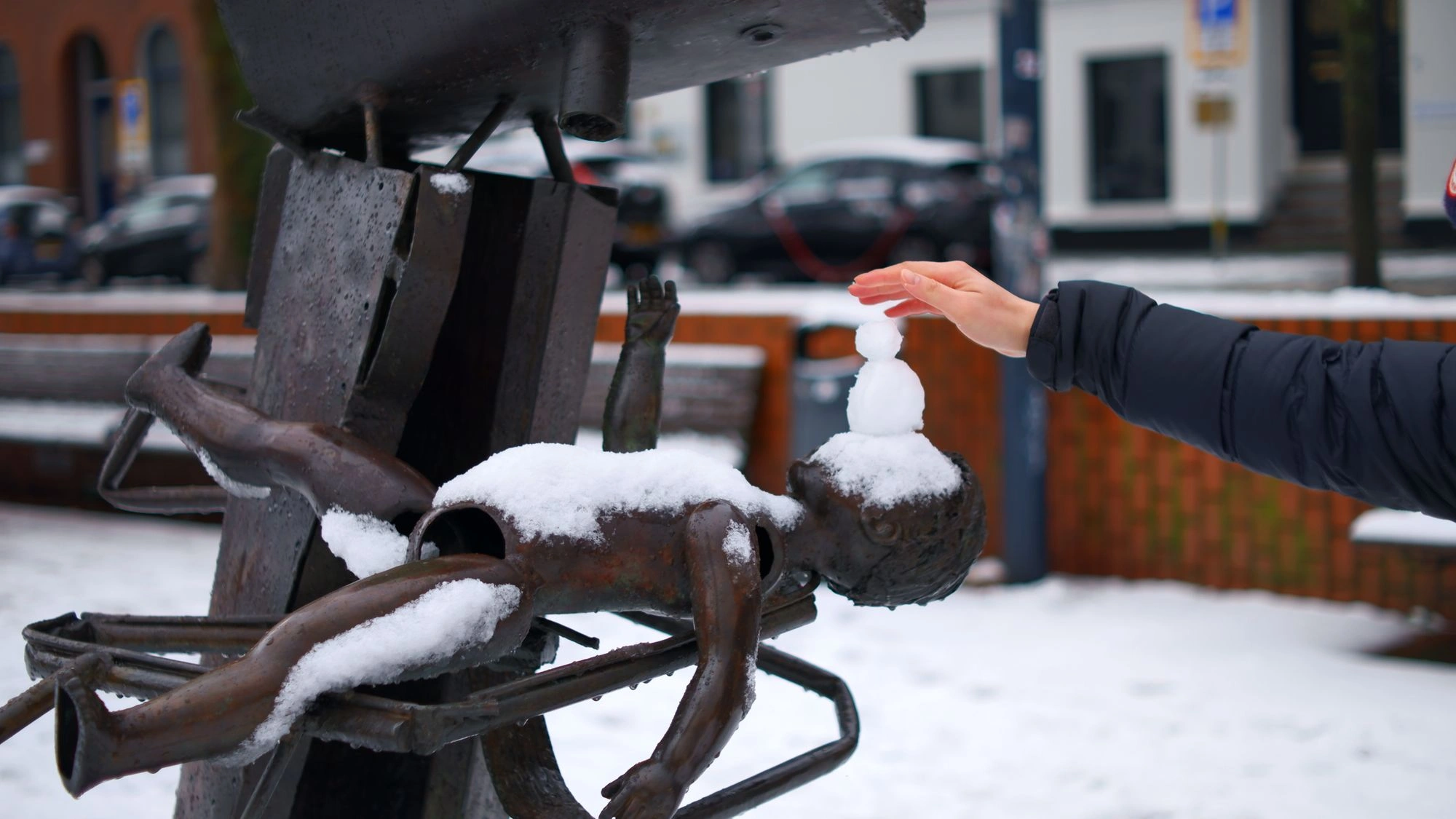 Hand touching the touch of a snowman on to of an abstract sculpture of a child.J